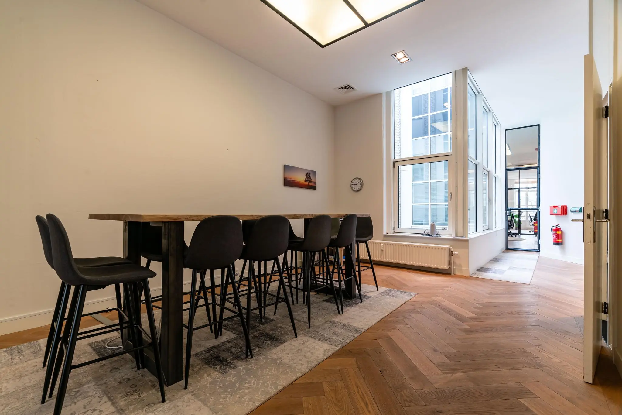 Vergaderruimte met hoge tafel en barkrukken aan de Lange Vijverberg, met uitzicht op een modern kantoorinterieur.